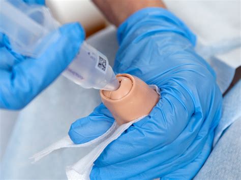 The patient has <strong>an indwelling urinary catheter</strong>. . A nurse is preparing a sterile field in order to insert an indwelling urinary catheter